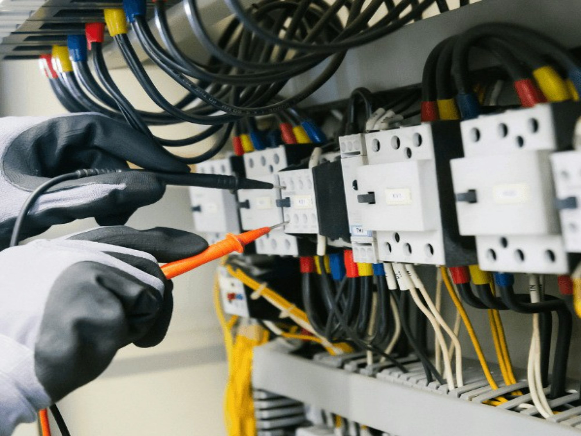 Electrician testing an industrial control panel with a multimeter